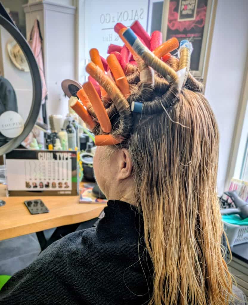 Brown-haired woman getting hairstyling with hair curlers at Salon 2 Go.