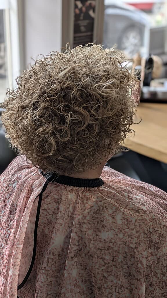 Kort gekruld haar met volume, klaar voor een nieuwe look.