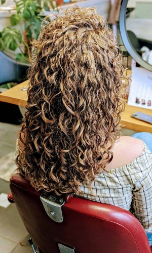 Gekrulde, lang haar in een salonstoel.